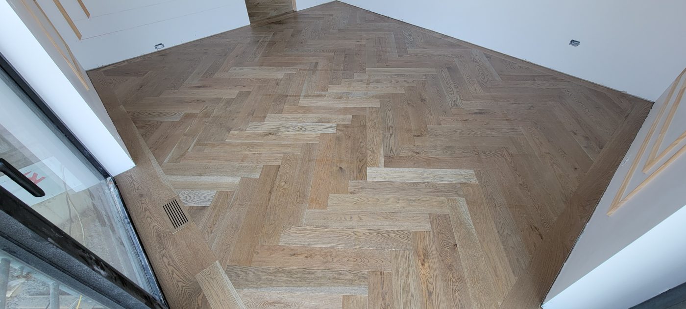 Plancher à chevrons en chêne blanchi, bordure périmétrique et grille de bois