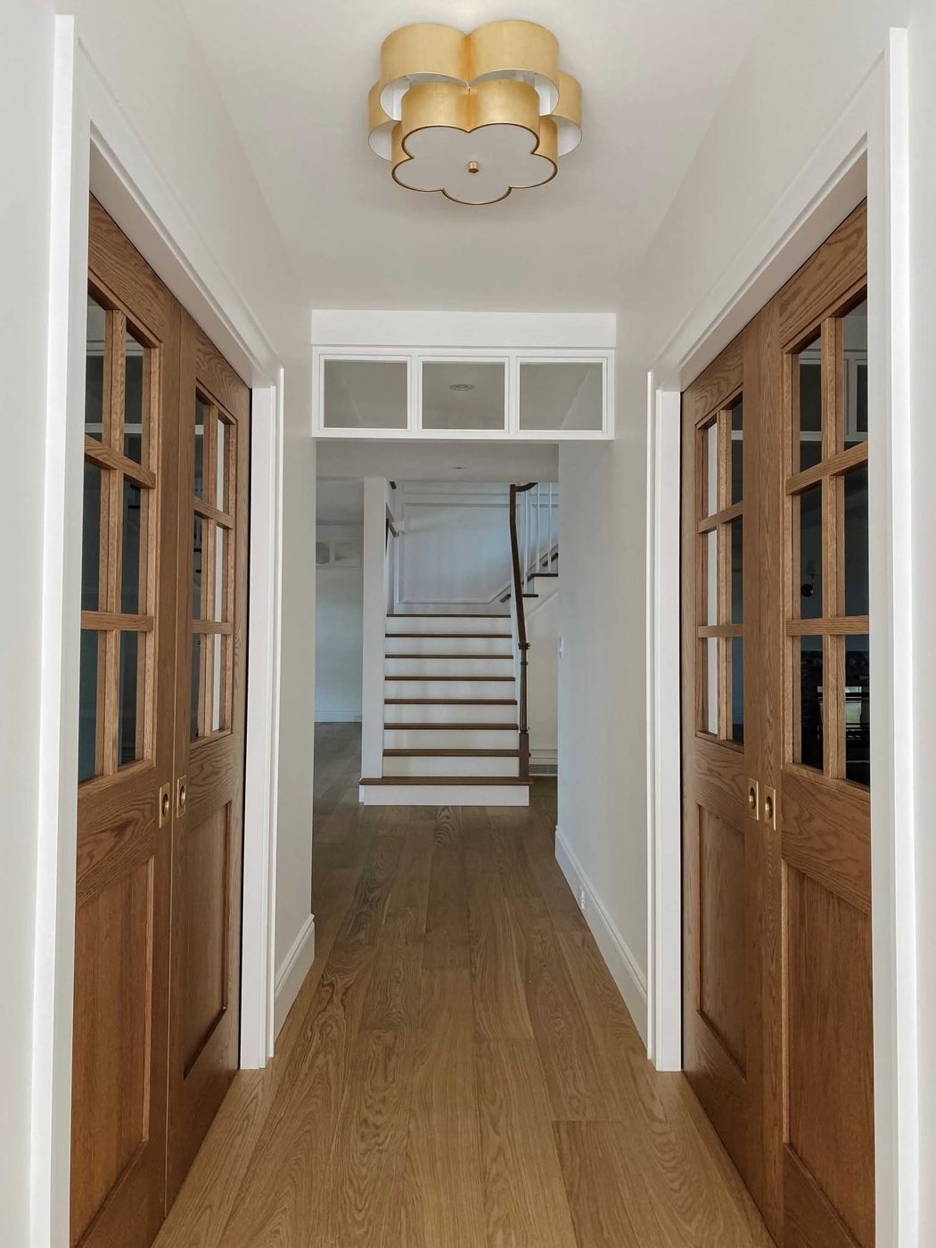 Couloir en chêne avec portes vitrées et escalier blanc Couloir en chêne avec portes vitrées et escalier blanc