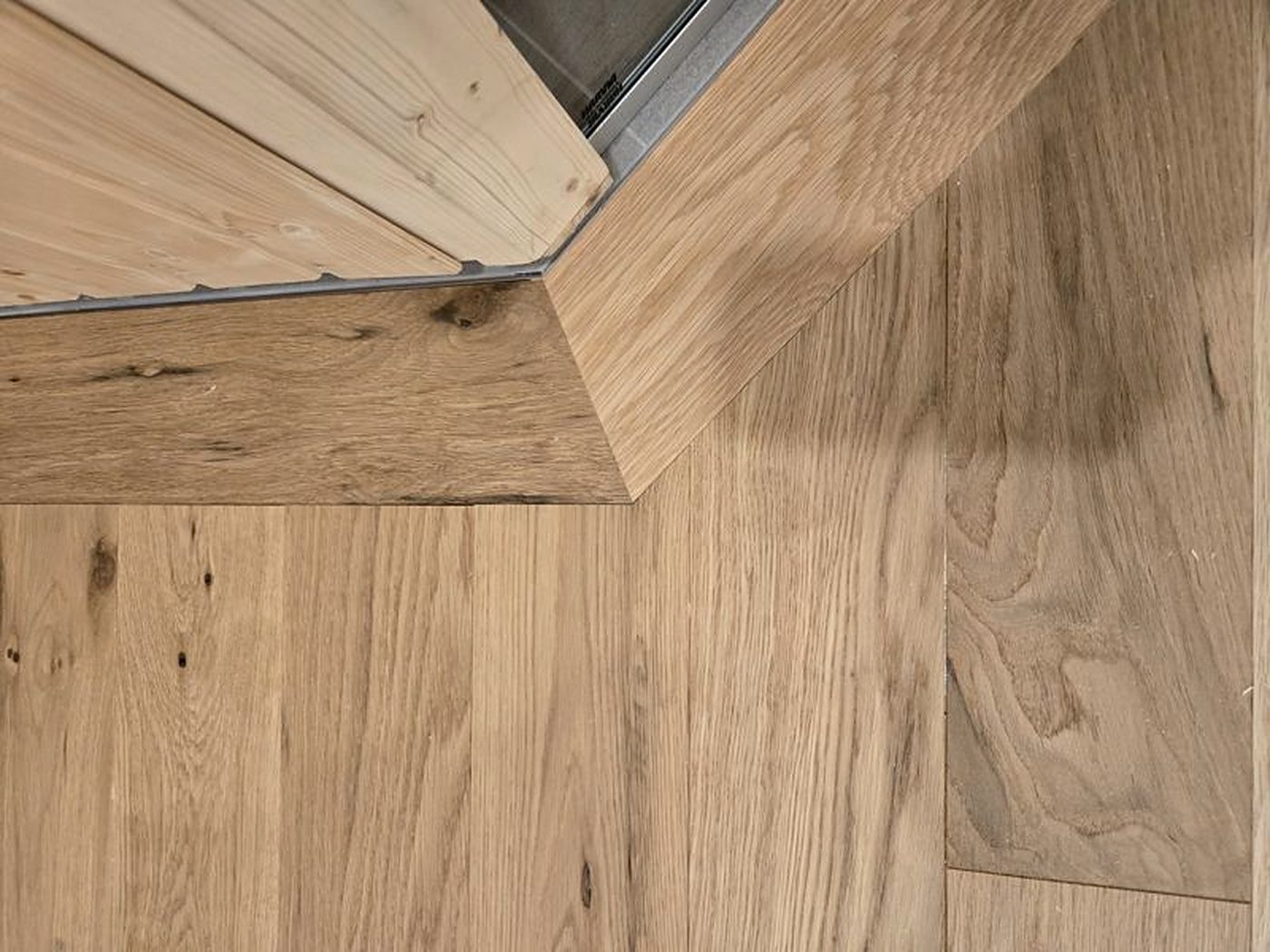 Plancher à chevrons en noyer menant au foyer de pierre et aux portes-fenêtres, Potton Détail de jonction de planches de chêne brossé au seuil, Mansonville
