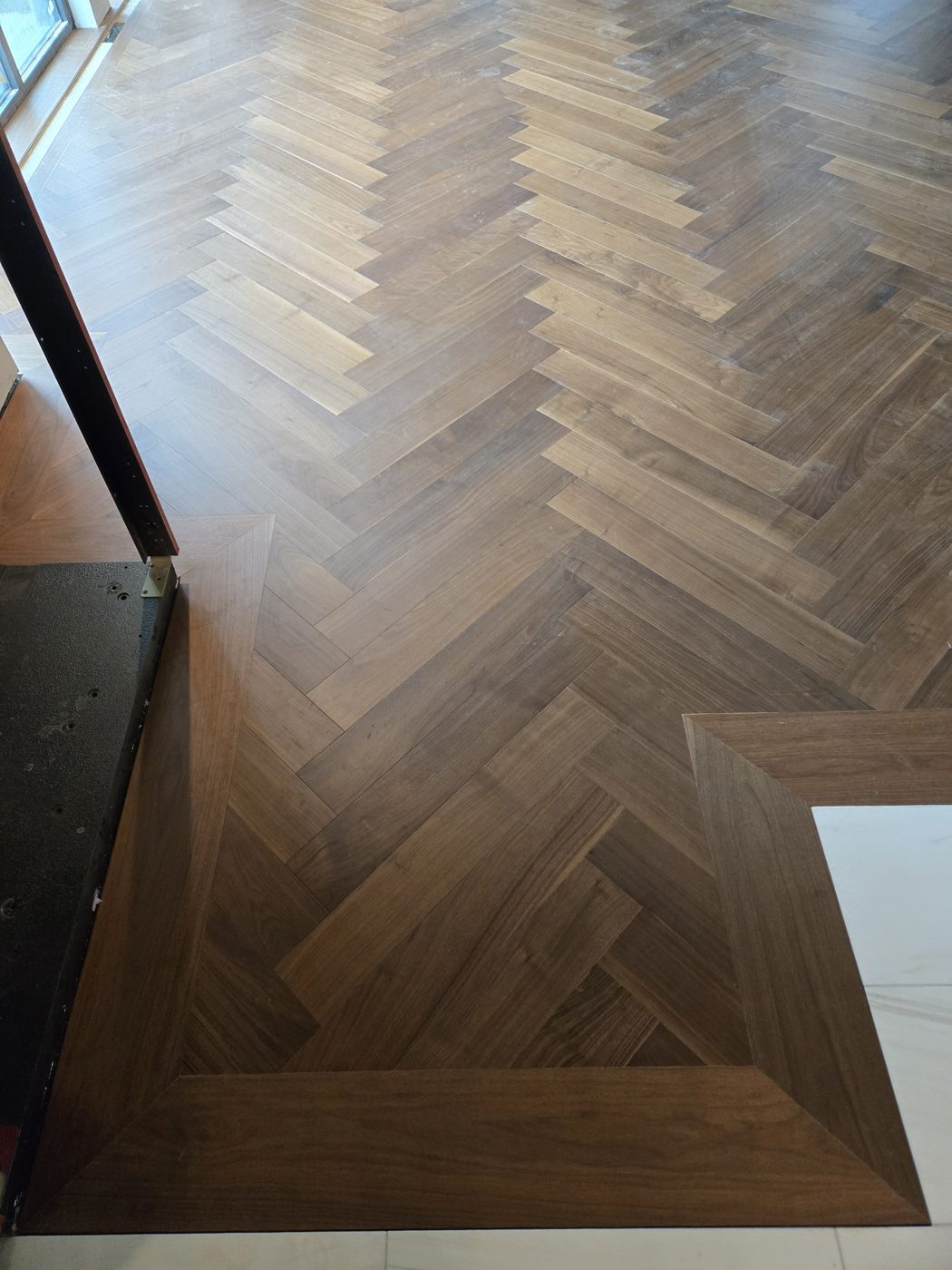 Détail de pose : chevrons en noyer avec frise de bordure droite Détail de pose : chevrons en noyer avec frise de bordure droite
