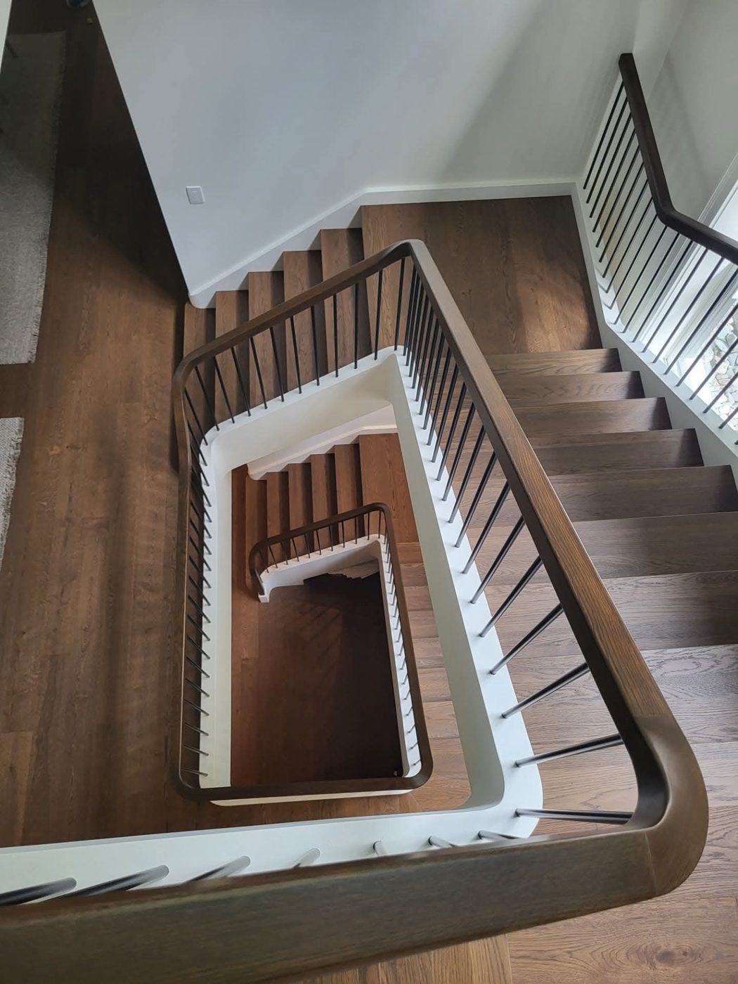 Escalier en bois franc vu du haut avec rampe noire