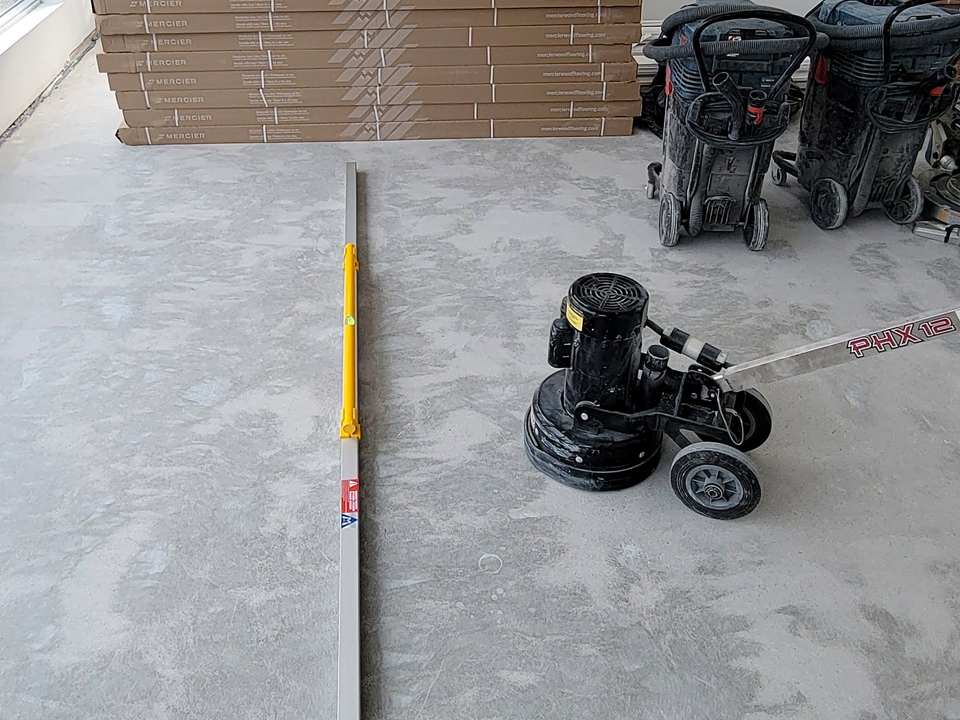 Meuleuse à béton planétaire et aspirateur HEPA sur une dalle avant la pose du plancher, Estrie