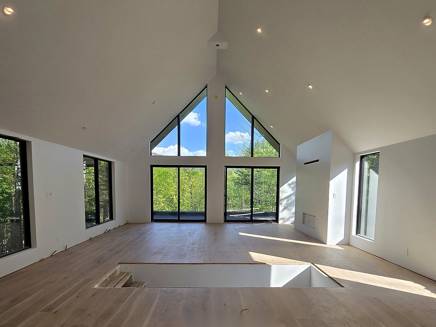 Grande pièce rénovée avec vue sur le lac à Magog Plancher de bois franc dans une pièce à plafond cathédrale et grandes fenêtres, Estrie