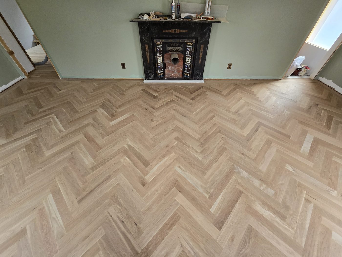 Plancher à chevrons en chêne blanc et foyer, vue large du salon Plancher à chevrons en chêne blanc et foyer, vue large du salon